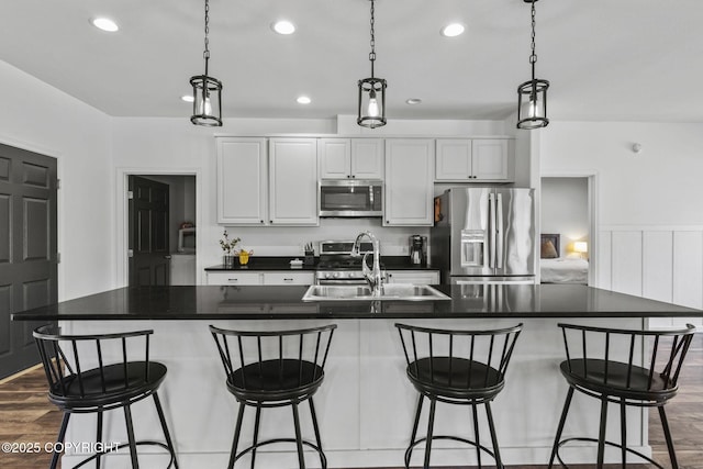 37653 Deville Rd, Soldotna, AK 99669 - kitchen featuring appliances with stainless steel finishes, a sink, recessed lighting, dark countertops, and a center island with sink
