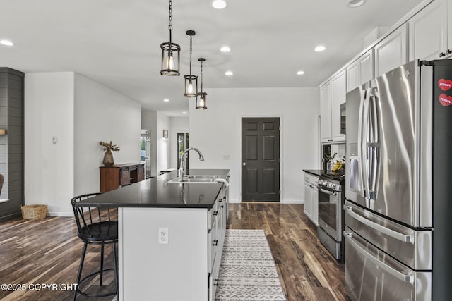 37653 Deville Rd, Soldotna, AK 99669 - kitchen with stainless steel appliances, a sink, dark countertops, a center island with sink, and white cabinetry