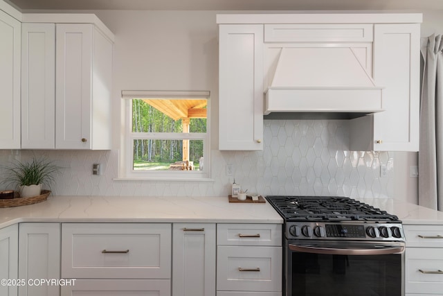 1645 N Vroman Dr, Palmer, AK 99645 - kitchen with stainless steel gas stove, premium range hood, white cabinets, and decorative backsplash