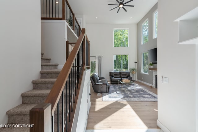 1645 N Vroman Dr, Palmer, AK 99645 - living room featuring wood finished floors, stairway, ceiling fan, a towering ceiling, and a fireplace