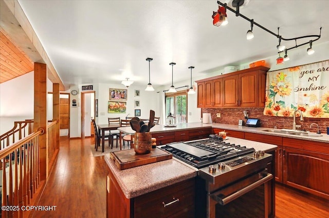 7965 S Settlers Bay Dr, Wasilla, AK 99623 - kitchen with stainless steel gas stove, a sink, backsplash, wood finished floors, and a kitchen island