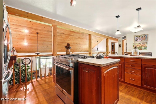 7965 S Settlers Bay Dr, Wasilla, AK 99623 - kitchen featuring stainless steel range with gas stovetop, fridge, wood finished floors, a center island, and pendant lighting