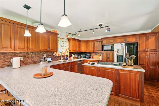 7965 S Settlers Bay Dr, Wasilla, AK 99623 - kitchen featuring stainless steel appliances, a sink, brown cabinetry, a peninsula, and light countertops