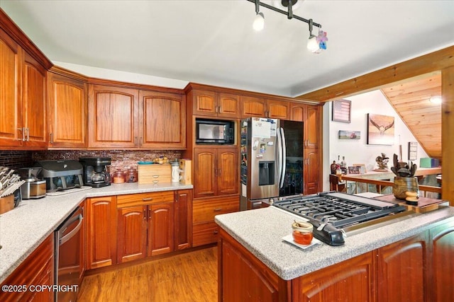7965 S Settlers Bay Dr, Wasilla, AK 99623 - kitchen featuring stainless steel appliances, light wood-type flooring, tasteful backsplash, brown cabinetry, and vaulted ceiling