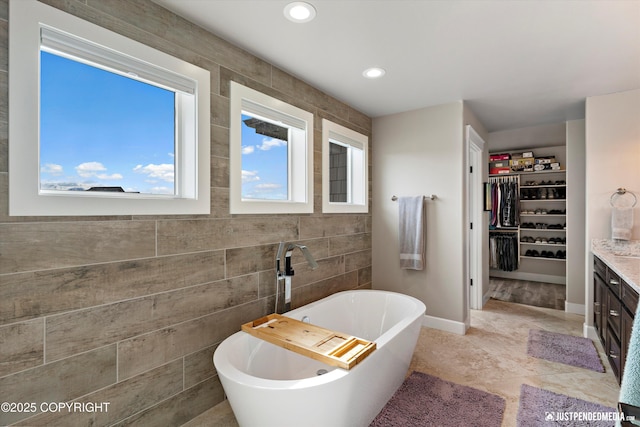 5167 E Henhouse Loop, Wasilla, AK 99654 - bathroom with a freestanding tub, vanity, tile walls, a spacious closet, and recessed lighting