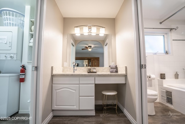 2503 Cedar St, Seward, AK 99664 - bathroom featuring stacked washer / drying machine, a bathtub, toilet, vanity, and baseboards