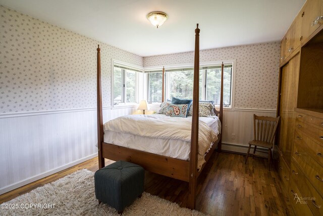 2503 Cedar St, Seward, AK 99664 - bedroom featuring wallpapered walls, a wainscoted wall, baseboard heating, and wood finished floors