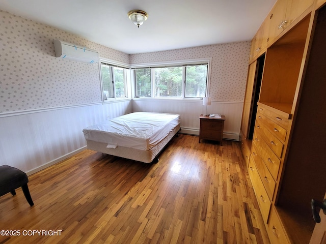2503 Cedar St, Seward, AK 99664 - bedroom featuring a wainscoted wall, a wall unit AC, light wood-style flooring, wallpapered walls, and a baseboard heating unit