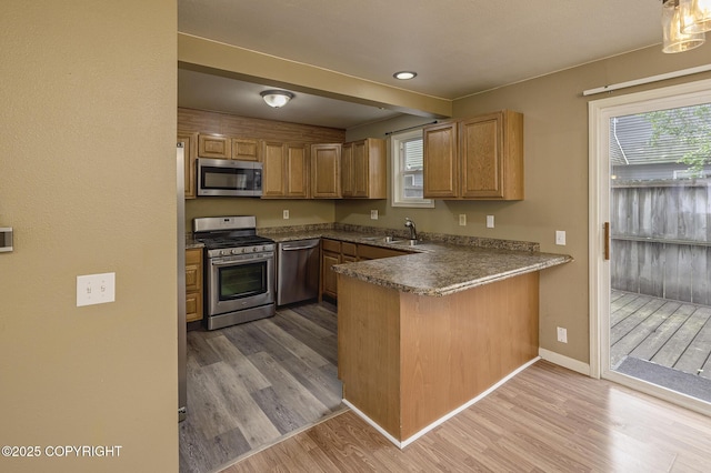4012 Reka Dr # G5, Anchorage, AK 99508 - kitchen featuring stainless steel appliances, a sink, wood finished floors, a peninsula, and baseboards