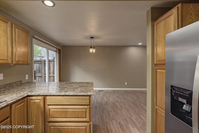 4012 Reka Dr # G5, Anchorage, AK 99508 - kitchen with stainless steel fridge, wood finished floors, a peninsula, brown cabinetry, and recessed lighting