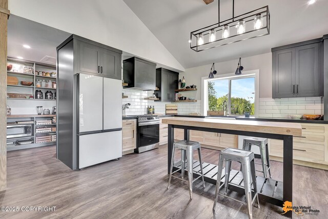 16111 E Nosey Ave, Talkeetna, AK 99676 - kitchen featuring stainless steel gas range, freestanding refrigerator, custom range hood, open shelves, and vaulted ceiling