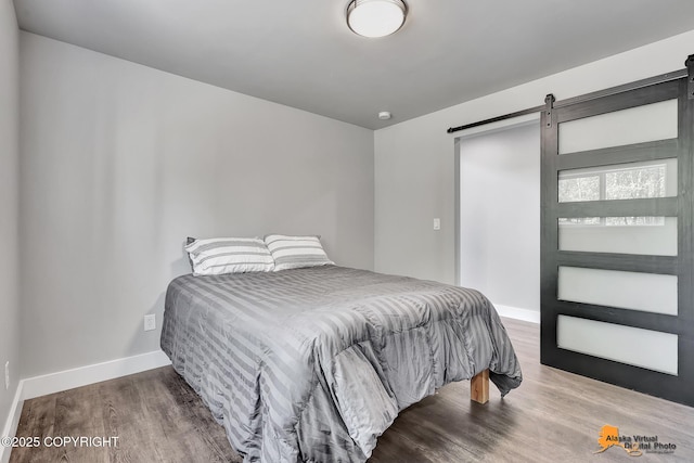 16111 E Nosey Ave, Talkeetna, AK 99676 - bedroom featuring a barn door, wood finished floors, and baseboards