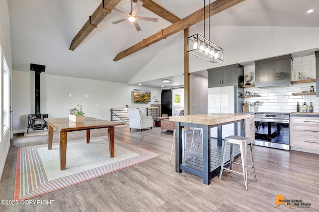 16111 E Nosey Ave, Talkeetna, AK 99676 - kitchen featuring stainless steel stove, open shelves, custom range hood, a wood stove, and high vaulted ceiling