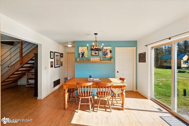 34540 Poppy Wood St, Soldotna, AK 99669 - dining area featuring a chandelier, light wood-style floors, and stairs