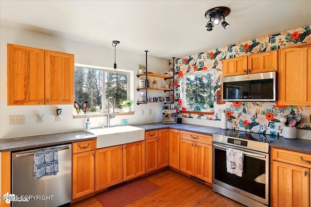 34540 Poppy Wood St, Soldotna, AK 99669 - kitchen featuring appliances with stainless steel finishes, light wood-style flooring, dark countertops, open shelves, and hanging light fixtures