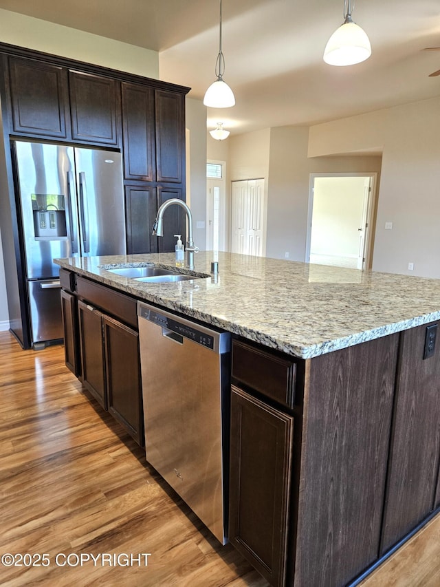 5523 Grand Teton Loop, Anchorage, AK 99502 - kitchen with appliances with stainless steel finishes, a sink, an island with sink, light wood-type flooring, and pendant lighting