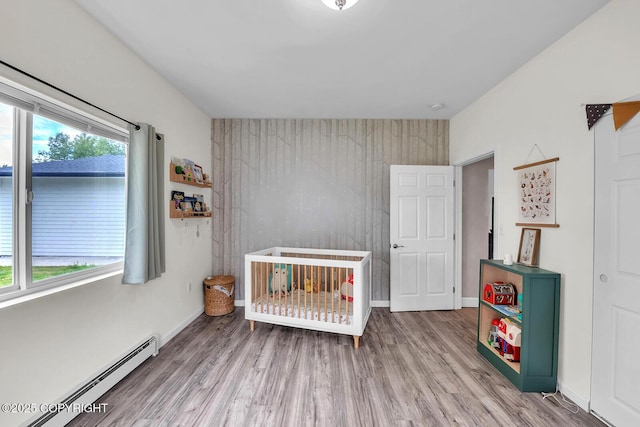 4850 N Riverstone Cir, Palmer, AK 99645 - bedroom with baseboard heating, wood finished floors, a crib, and an accent wall