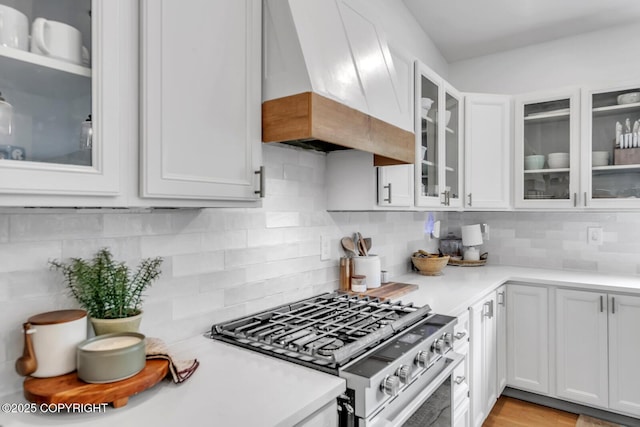 4850 N Riverstone Cir, Palmer, AK 99645 - kitchen featuring stainless steel range with gas cooktop, custom range hood, light countertops, tasteful backsplash, and white cabinetry