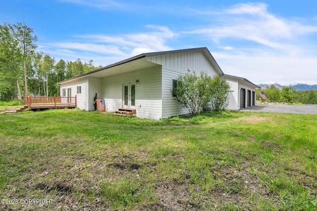 4850 N Riverstone Cir, Palmer, AK 99645 - view of side of property featuring an attached garage, a deck with mountain view, french doors, a lawn, and asphalt driveway