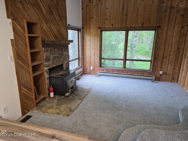 5650 N Talgach View Dr, Wasilla, AK 99654 - carpeted living room featuring a wood stove, baseboard heating, and wood walls