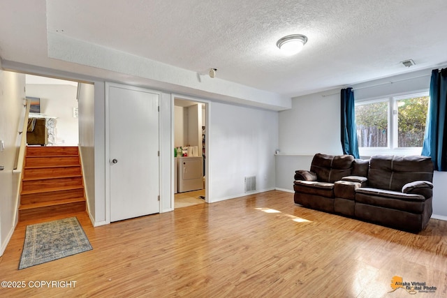 3040 Rosalind Loop, Anchorage, AK 99507 - living room featuring a textured ceiling, washer / dryer, light wood finished floors, stairway, and baseboards