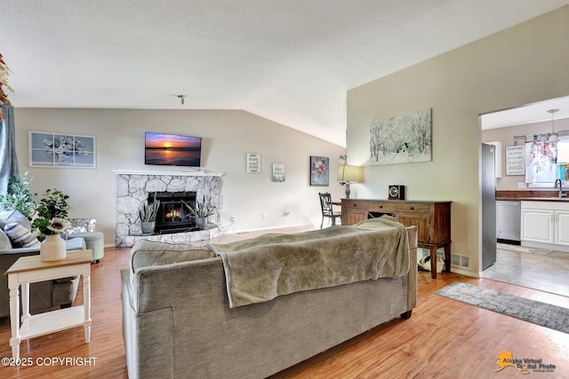 3040 Rosalind Loop, Anchorage, AK 99507 - living area featuring lofted ceiling, light wood finished floors, and a stone fireplace