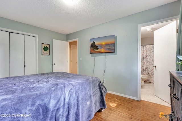 3040 Rosalind Loop, Anchorage, AK 99507 - bedroom with light wood finished floors, baseboards, a textured ceiling, ensuite bath, and a closet