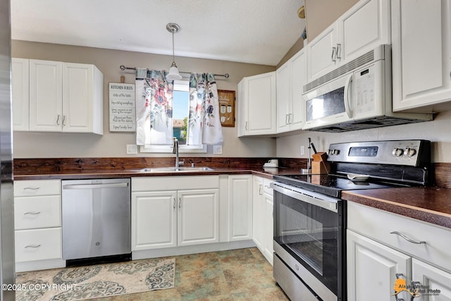 3040 Rosalind Loop, Anchorage, AK 99507 - kitchen featuring appliances with stainless steel finishes, a sink, dark countertops, white cabinets, and hanging light fixtures