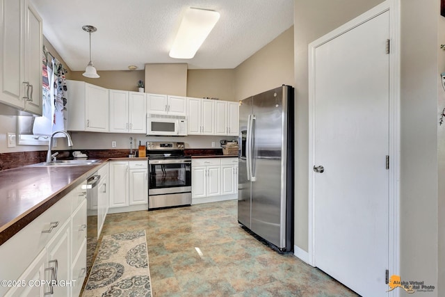 3040 Rosalind Loop, Anchorage, AK 99507 - kitchen with stainless steel appliances, a sink, dark countertops, white cabinetry, and lofted ceiling