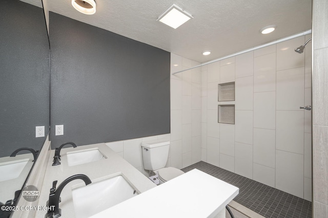13311 Cove Cir, Anchorage, AK 99515 - bathroom with tiled shower, a textured ceiling, recessed lighting, and double vanity