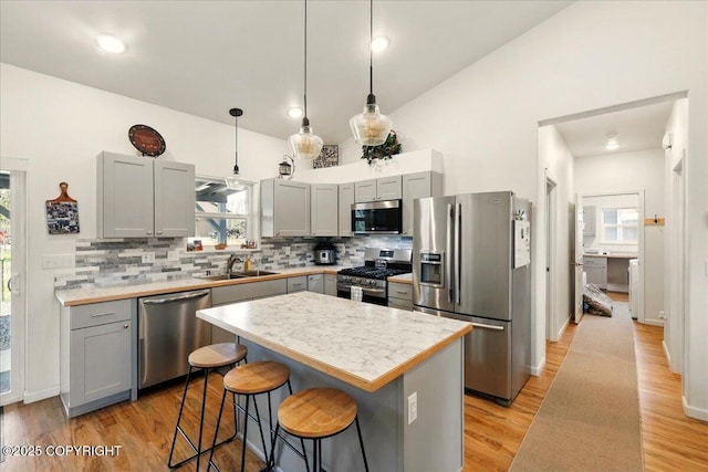 47974 Barney Ct, Soldotna, AK 99669 - kitchen featuring appliances with stainless steel finishes, a sink, gray cabinets, tasteful backsplash, and a breakfast bar area
