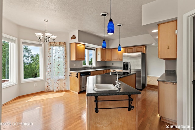 18704 Snowy Plover Cir, Anchorage, AK 99516 - kitchen with appliances with stainless steel finishes, a kitchen island with sink, a sink, light wood-style floors, and a chandelier
