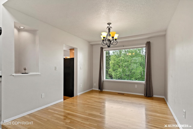 18704 Snowy Plover Cir, Anchorage, AK 99516 - unfurnished room with a chandelier, wood finished floors, a textured ceiling, and baseboards