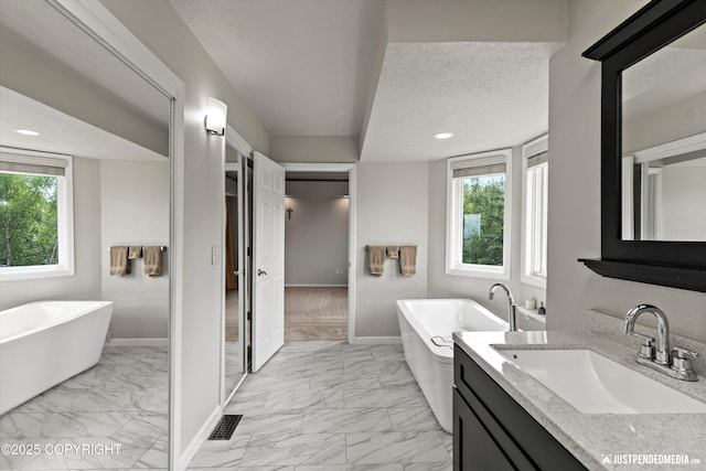18704 Snowy Plover Cir, Anchorage, AK 99516 - full bath featuring marble look tile flooring, vanity, baseboards, a freestanding bath, and recessed lighting