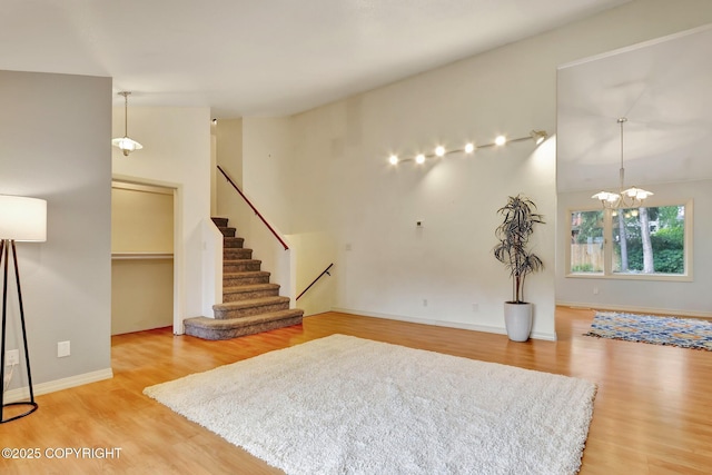 13521 Ebbtide Cir, Anchorage, AK 99516 - living room featuring light wood-style flooring, stairway, a chandelier, high vaulted ceiling, and baseboards