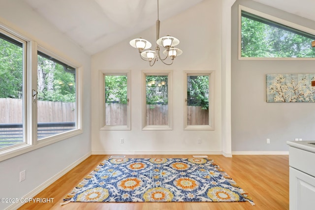 13521 Ebbtide Cir, Anchorage, AK 99516 - unfurnished dining area with plenty of natural light, a chandelier, light wood-style floors, vaulted ceiling, and baseboards
