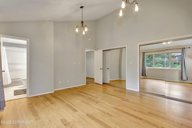 13521 Ebbtide Cir, Anchorage, AK 99516 - unfurnished bedroom with a chandelier, multiple closets, wood finished floors, high vaulted ceiling, and ensuite bathroom