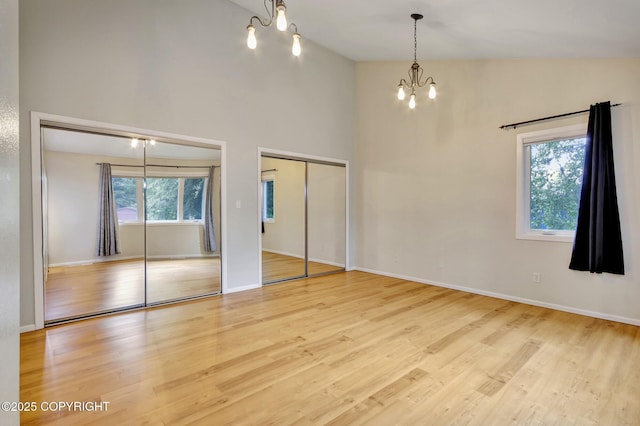 13521 Ebbtide Cir, Anchorage, AK 99516 - unfurnished bedroom with a chandelier, two closets, wood finished floors, a towering ceiling, and baseboards