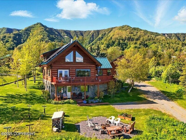 58820 E End Rd, Homer, AK 99603 - back of house with a deck with mountain view, a lawn, a view of trees, a fire pit, and log siding