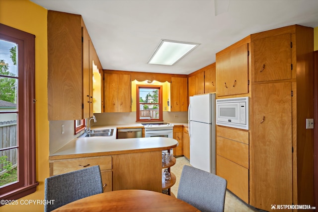1310 G St, Anchorage, AK 99501 - kitchen with white appliances, a sink, light countertops, a peninsula, and brown cabinetry