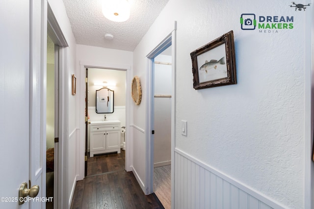190 Grand Larry St Unit A-01, Anchorage, AK 99504 - hall with dark wood-style flooring, a textured ceiling, and a wainscoted wall
