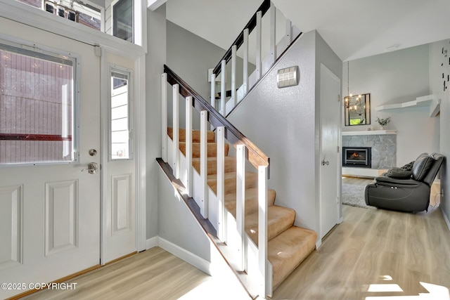 3370 Chaparral Cir, Anchorage, AK 99502 - entrance foyer featuring wood finished floors, a stone fireplace, stairs, baseboards, and a high ceiling