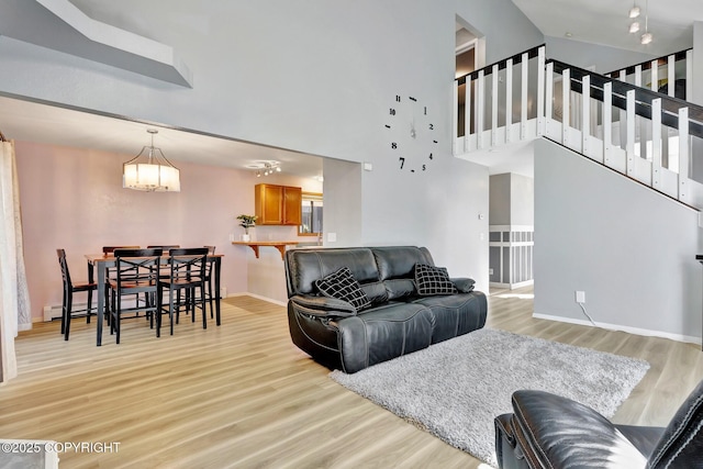 3370 Chaparral Cir, Anchorage, AK 99502 - living area featuring light wood-type flooring, a chandelier, baseboards, stairway, and a towering ceiling