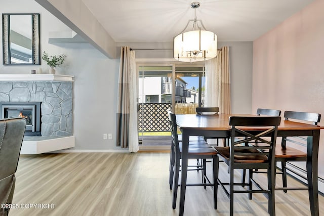 3370 Chaparral Cir, Anchorage, AK 99502 - dining area with a chandelier, wood finished floors, a stone fireplace, baseboards, and a baseboard radiator