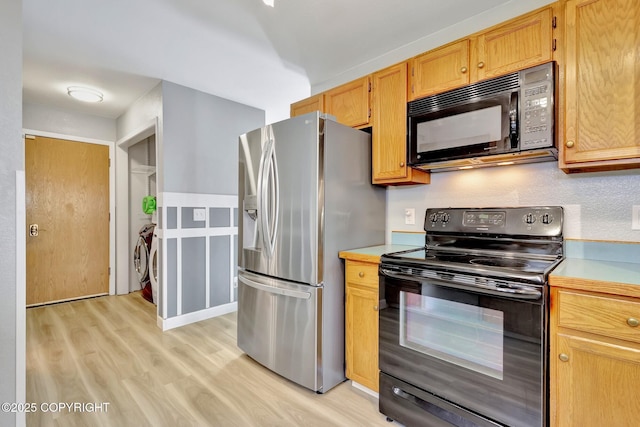 3370 Chaparral Cir, Anchorage, AK 99502 - kitchen featuring black appliances, light wood-style floors, light countertops, and separate washer and dryer