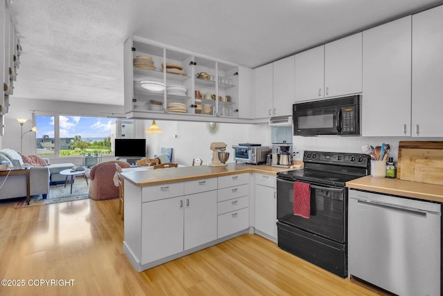 824 O Pl, Anchorage, AK 99501 - kitchen with black appliances, light wood-style floors, a peninsula, white cabinetry, and light countertops