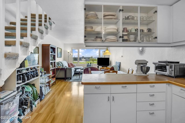 824 O Pl, Anchorage, AK 99501 - kitchen featuring light wood-type flooring, white cabinetry, open floor plan, and a peninsula