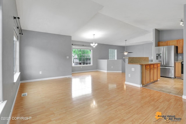 17480 Beaujolais Cir, Eagle River, AK 99577 - unfurnished living room featuring vaulted ceiling, a ceiling fan, light wood-type flooring, baseboards, and a chandelier
