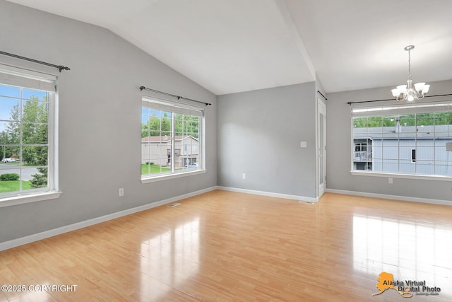 17480 Beaujolais Cir, Eagle River, AK 99577 - empty room with plenty of natural light, a chandelier, vaulted ceiling, light wood finished floors, and baseboards