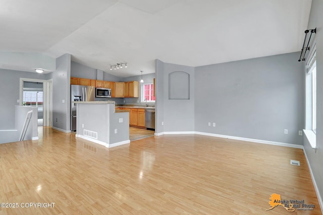 17480 Beaujolais Cir, Eagle River, AK 99577 - unfurnished living room with vaulted ceiling, light wood finished floors, baseboards, and rail lighting